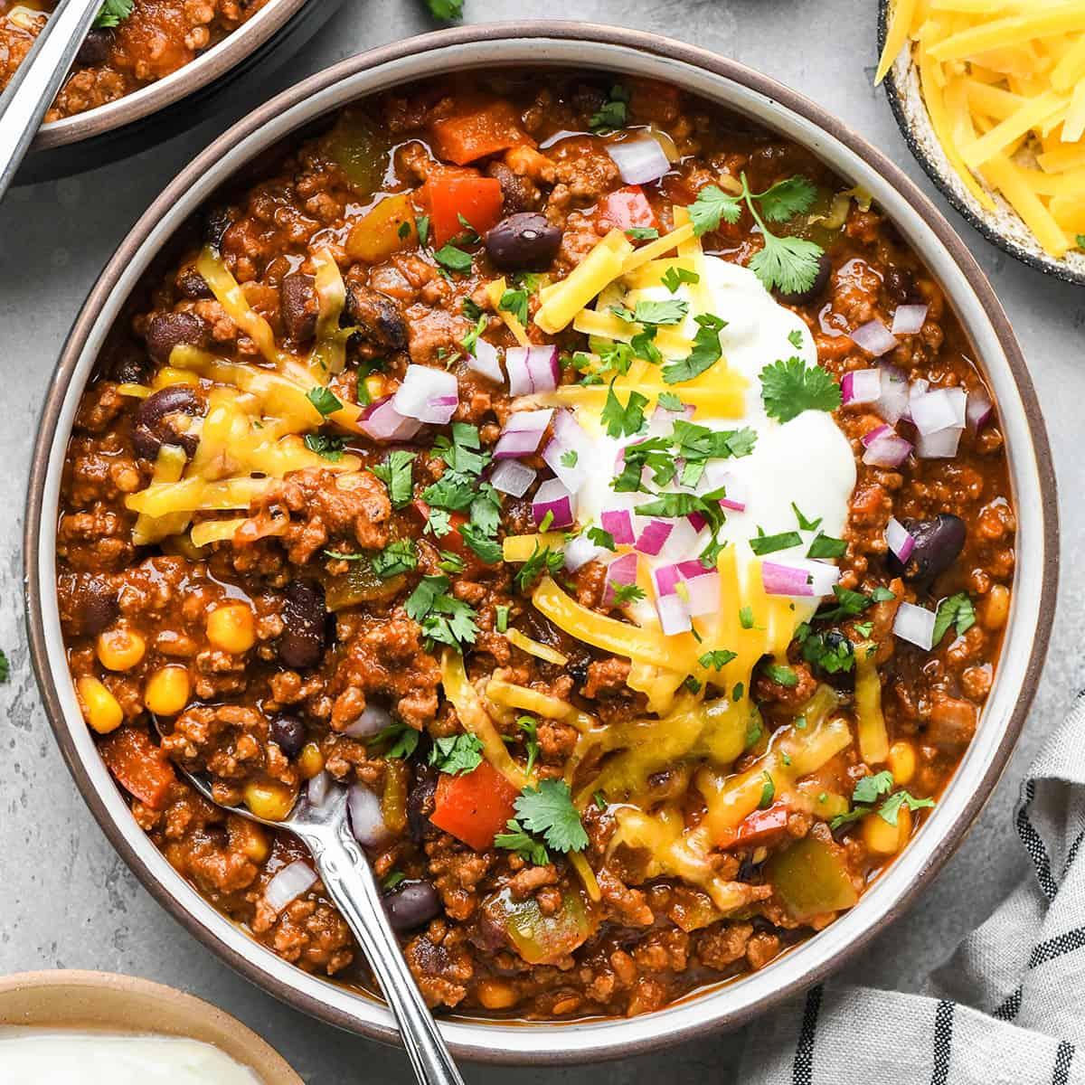 A hearty bowl of slow cooker chili with cumin, garnished with cilantro and sour cream