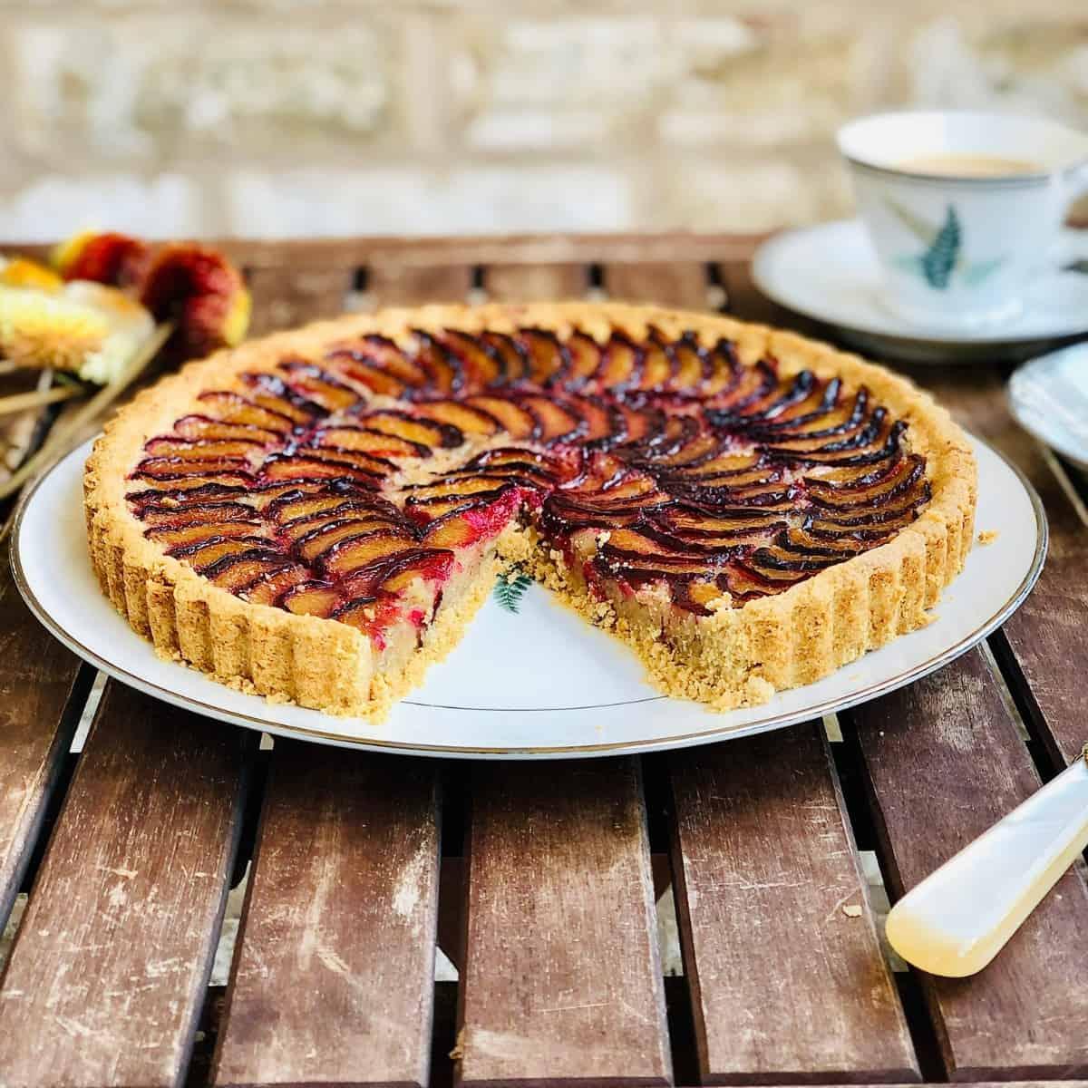 whole dairy-free plum tart on a wooden surface