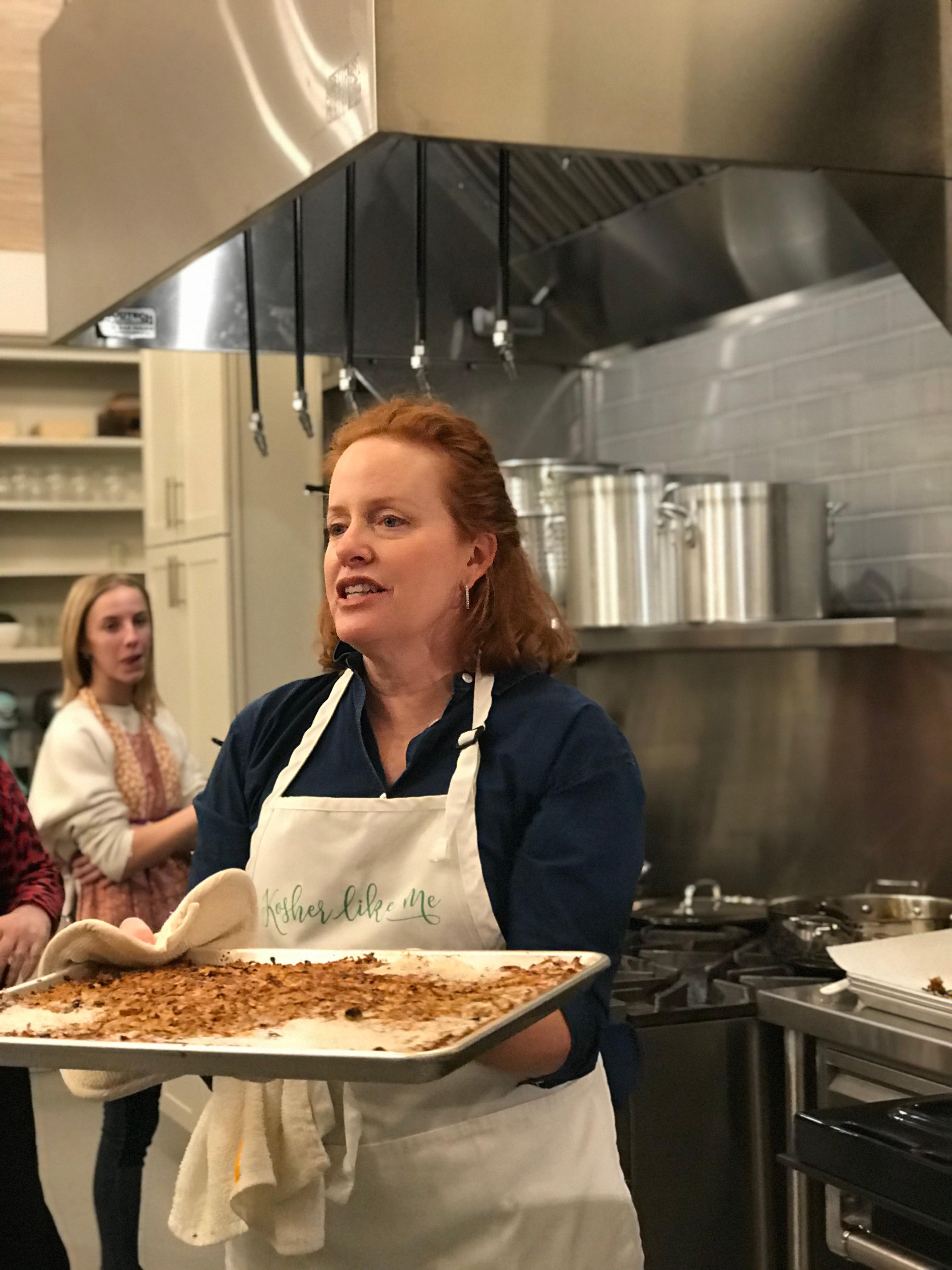 Chef Amelia Stone smiling, holding a plate of perfectly glazed smoked ribs