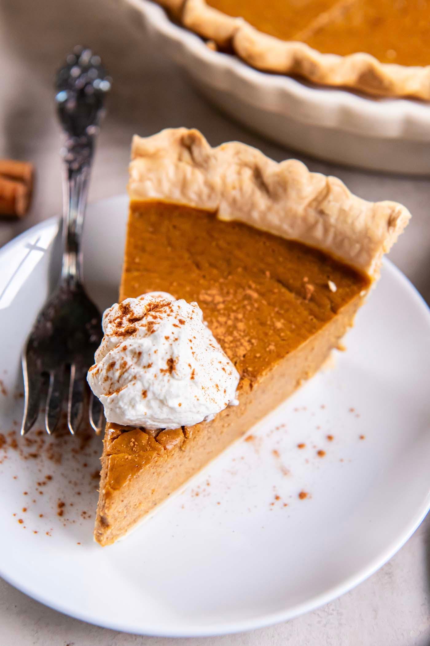 Smooth, vibrant orange pumpkin pie filling being poured into a partially baked pie crust