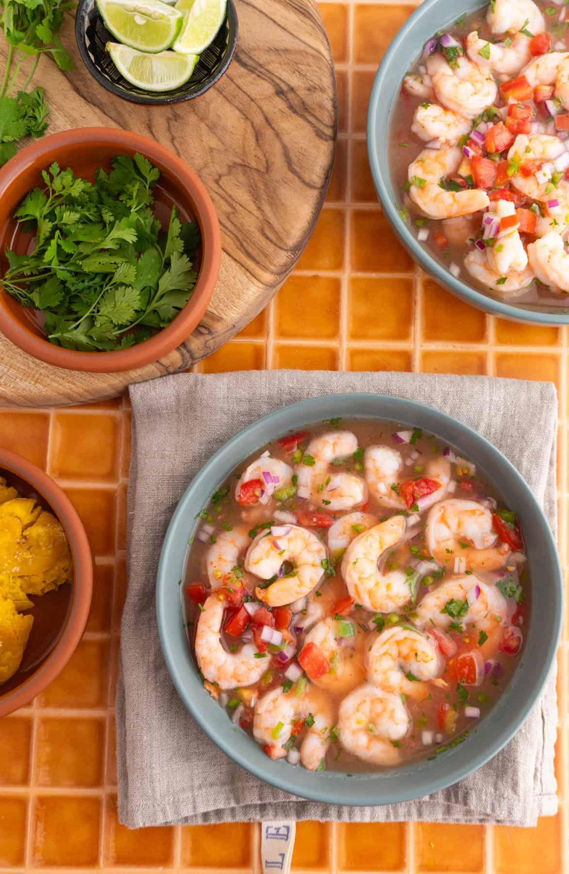 Ecuadorian Shrimp Ceviche with Passion Fruit garnished with fresh cilantro and lime wedges on a rustic wooden table