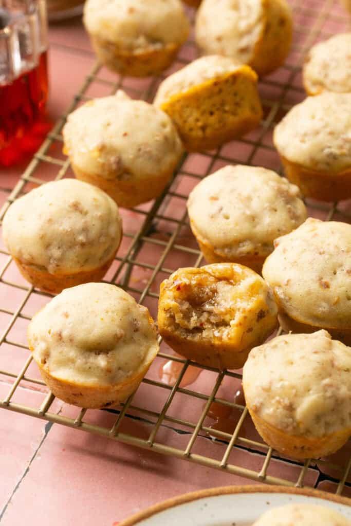 Batch of golden-brown cooked McGriddle bites cooling on a wire rack with a drizzle of maple syrup