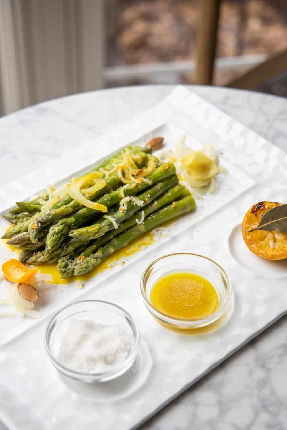chef shaving parmesan over champagne marinated asparagus