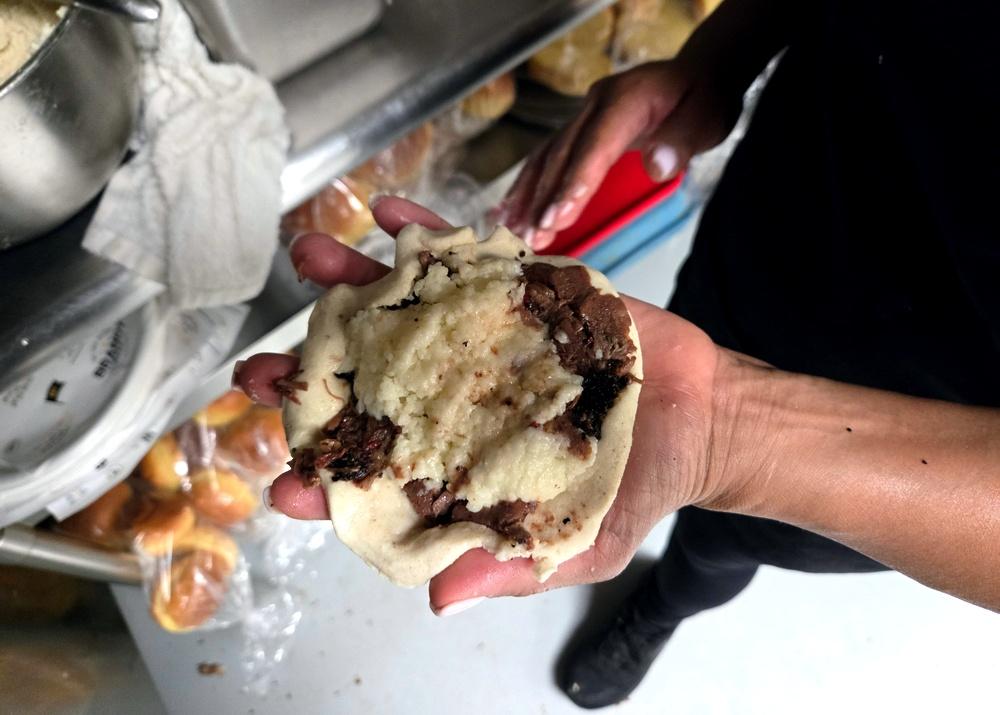 close-up shot of a smoked brisket pupusa being cut open, revealing the filling