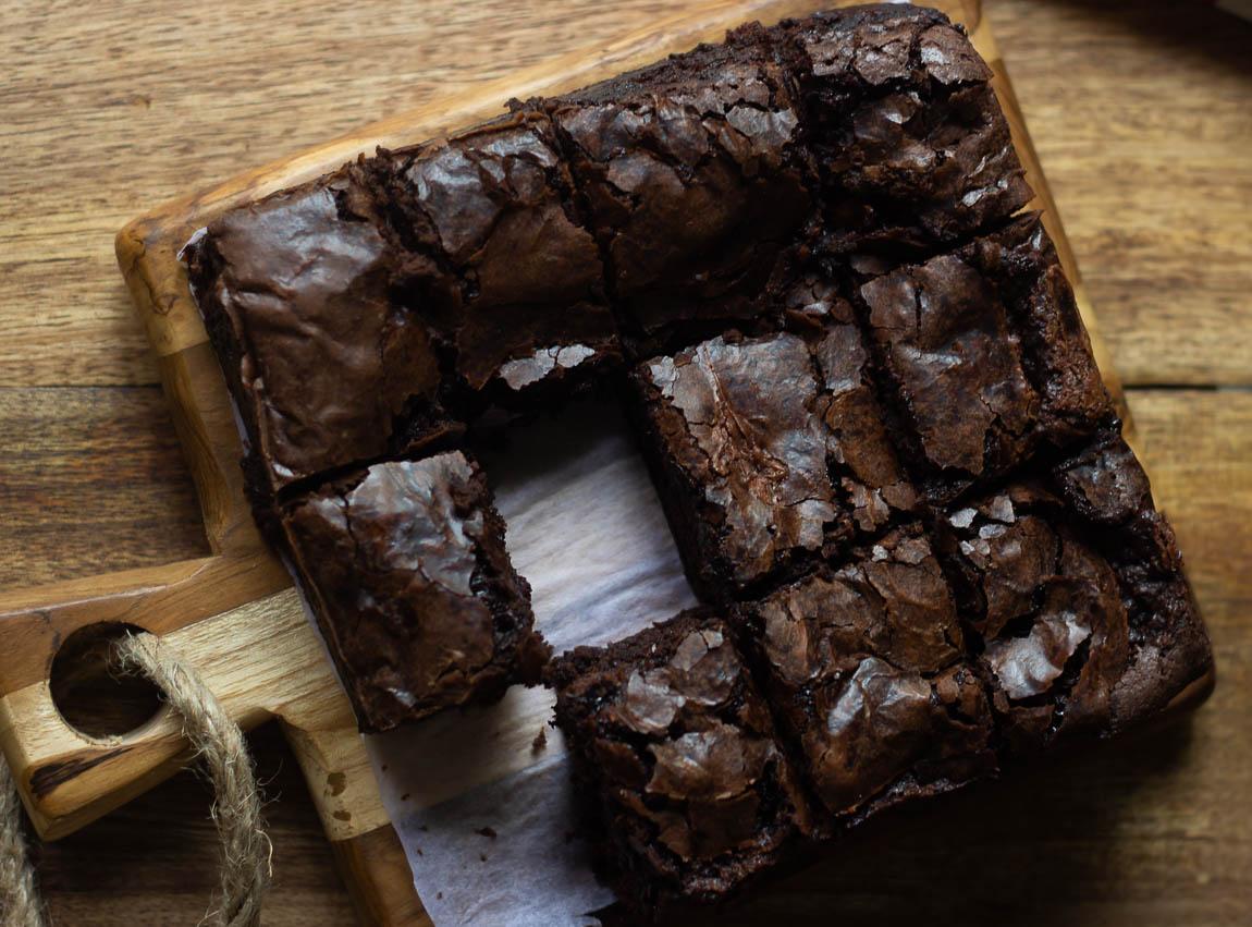 A close-up shot of a fudgy brownie with a slightly cracked top, showing the moist inside