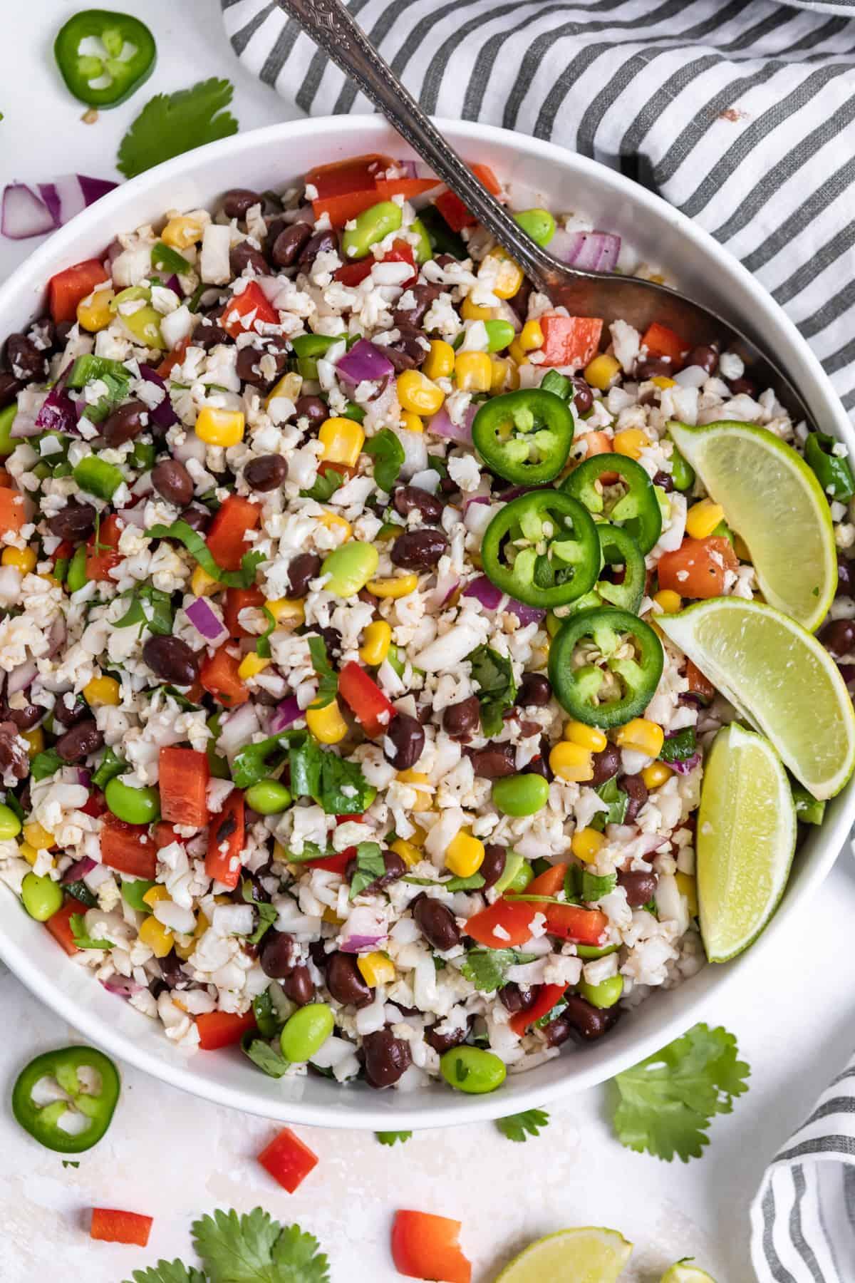 a bowl of cauliflower rice Caprese salad with a spoon, ready to be served