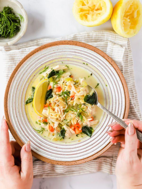 Close up shot of a spoon scooping Mediterranean Orzo Pasta Soup from a large bowl