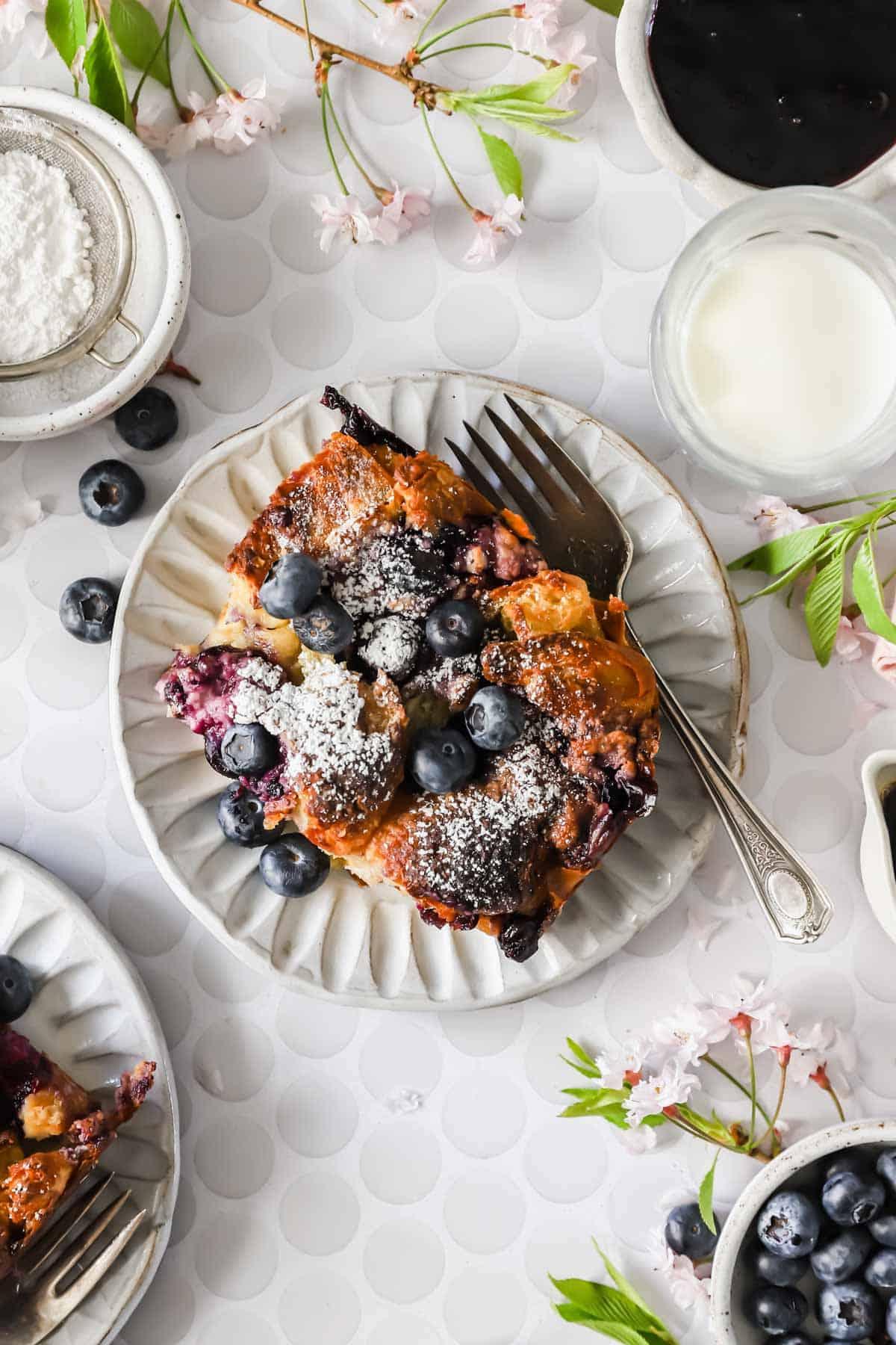 Smiling family enjoying blueberry french toast bake at breakfast table, natural light