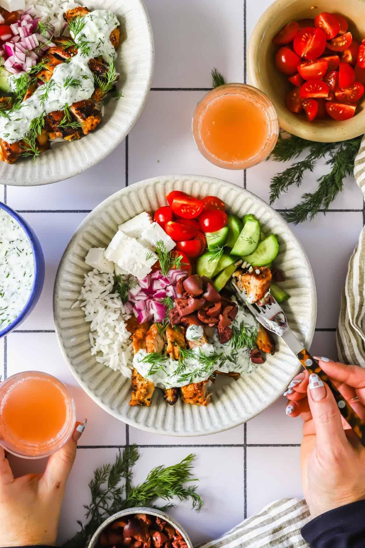 Vibrant Greek chicken bowl with tzatziki, cucumber, tomatoes, and feta on a rustic table