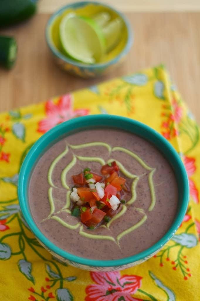 close-up of black bean soup with avocado crema being spooned into a bowl