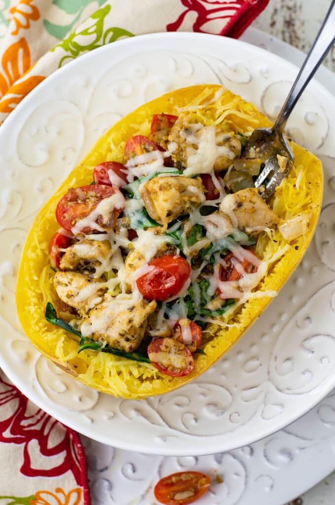 Close-up shot of cutting into a cooked spaghetti squash and spinach stuffed chicken breast, showing the filling