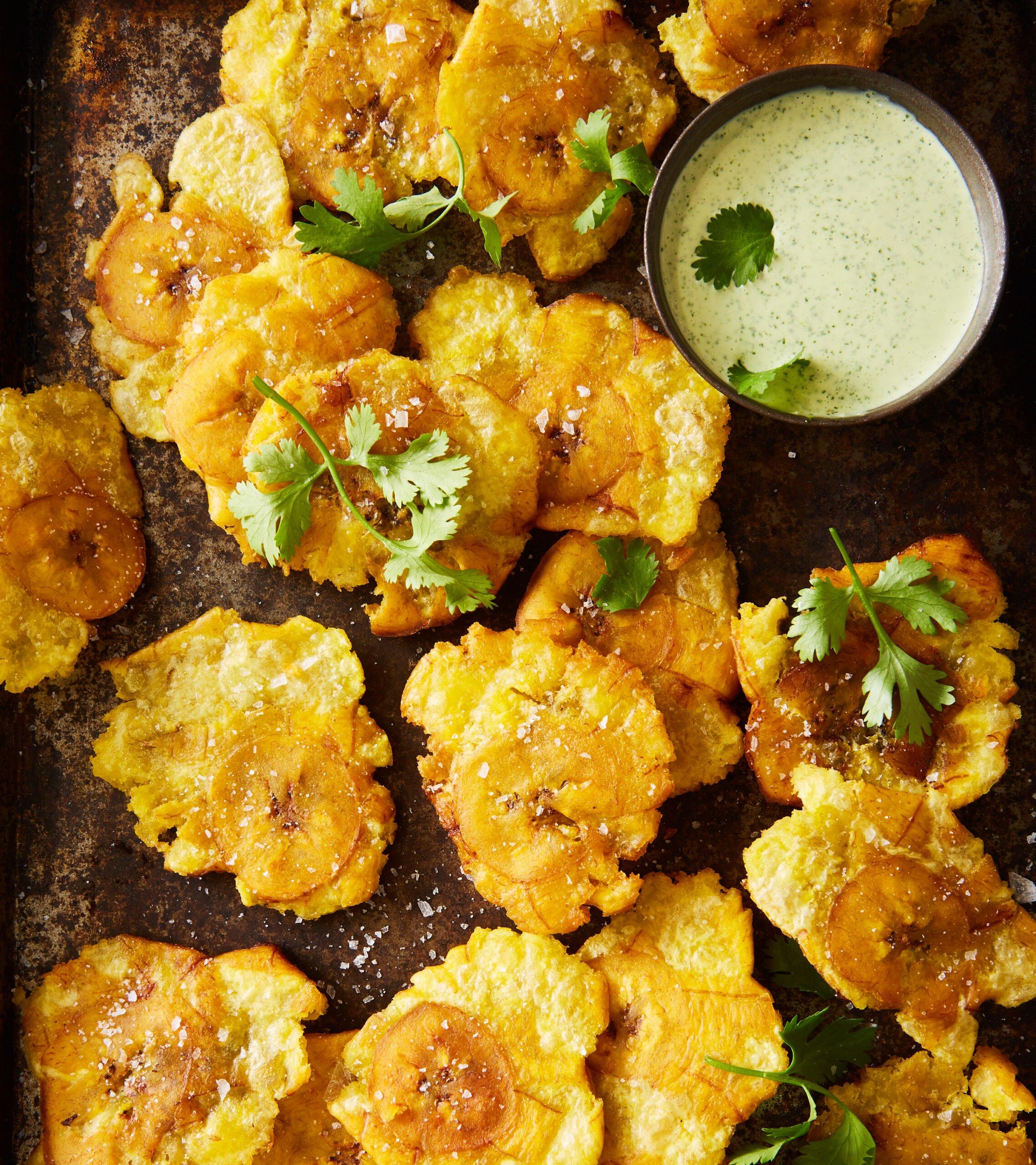 roasted plantain pieces arranged on a serving plate with lime wedges and cilantro