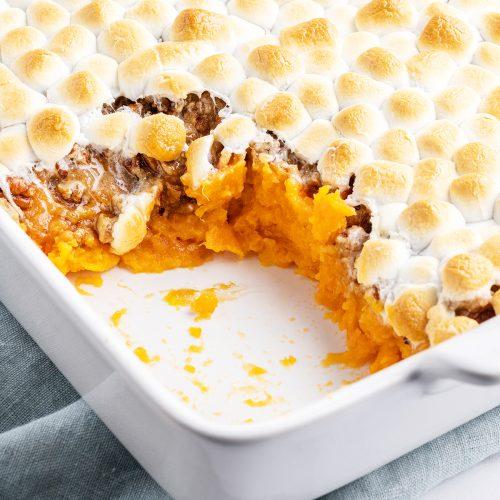 Close-up of golden brown toasted marshmallows on top of a sweet potato casserole in a baking dish