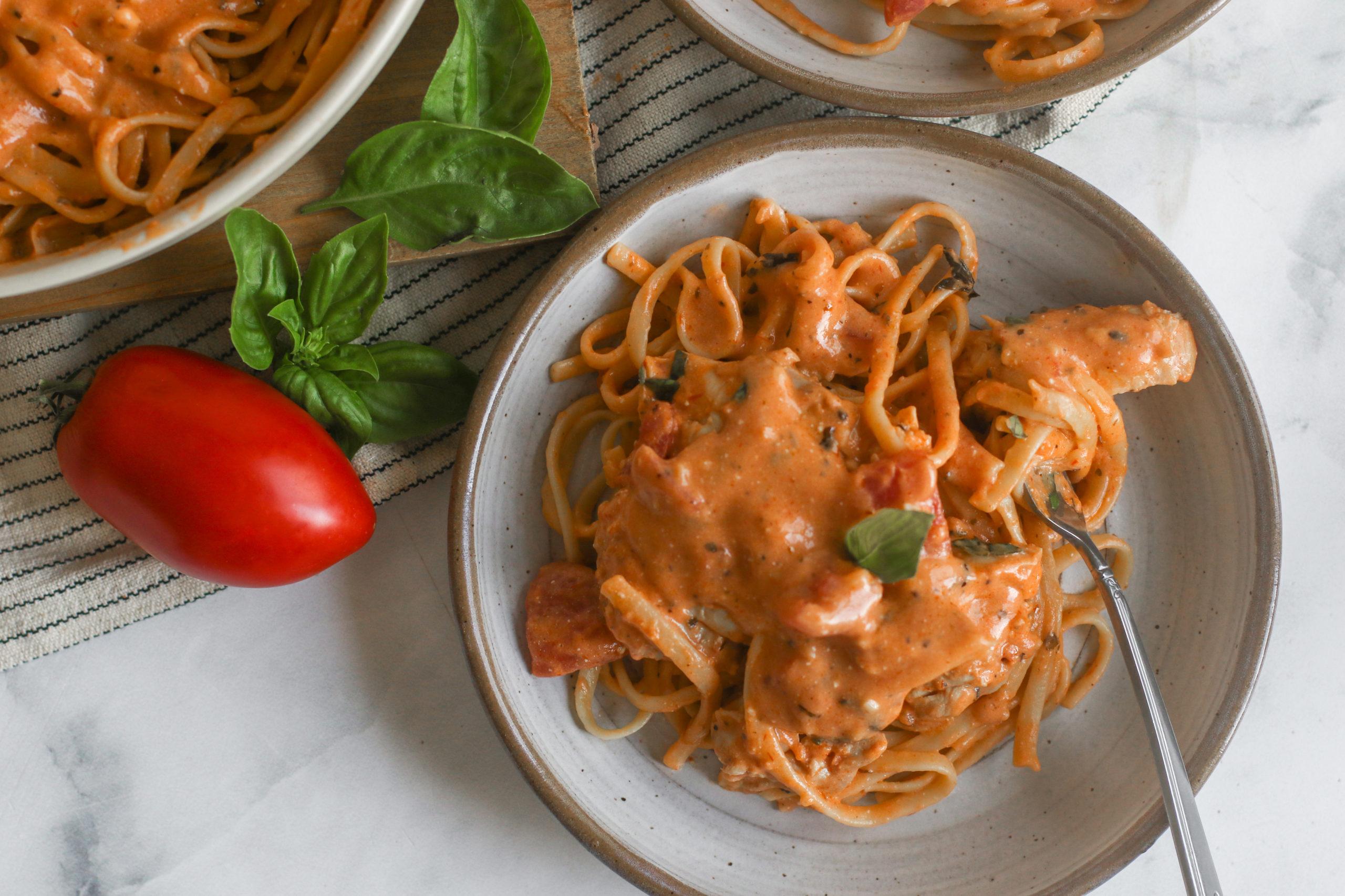 Crockpot creamy tomato chicken with pasta and fresh basil, cozy kitchen lighting