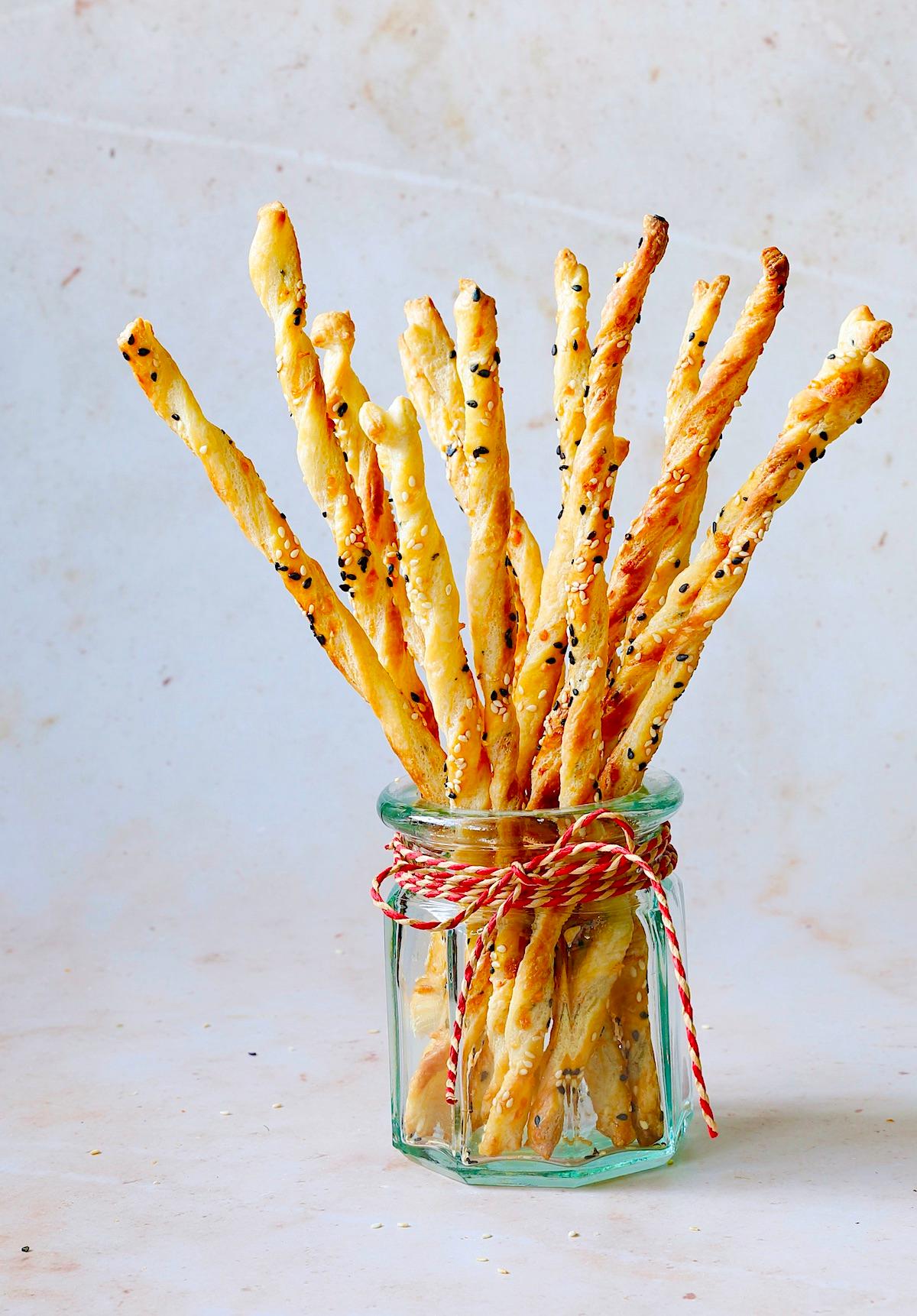 Person looking thoughtfully at puff pastry and Parmesan cheese in a kitchen counter