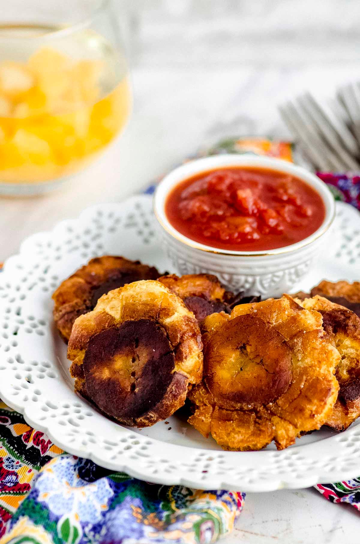 close up of sliced plantains being tossed with oil and seasonings in a bowl