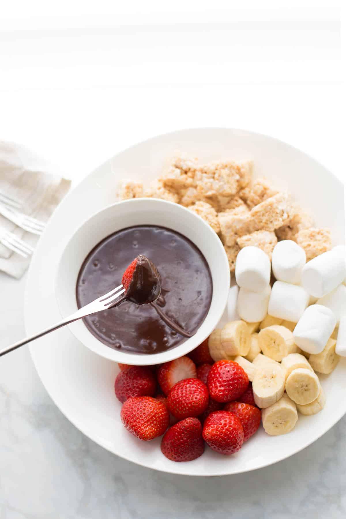 Overhead shot of raspberries being dipped into a chocolate fondue