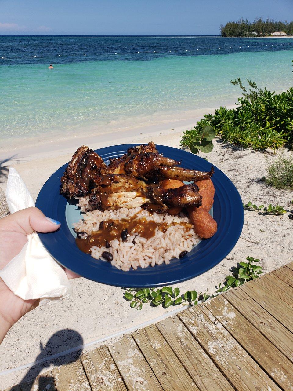 A family enjoying jerk chicken on a beach in Jamaica