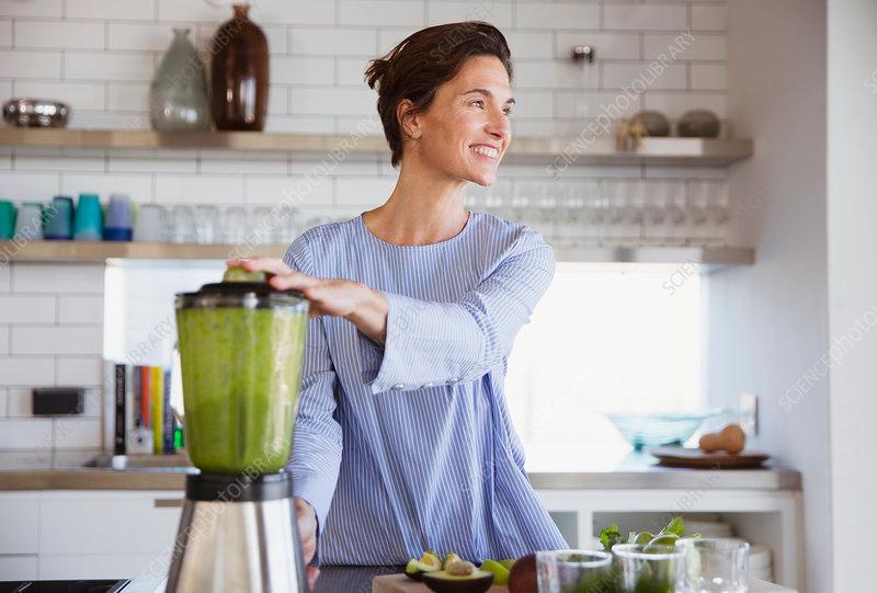 Woman making a healthy smoothie in a kitchen