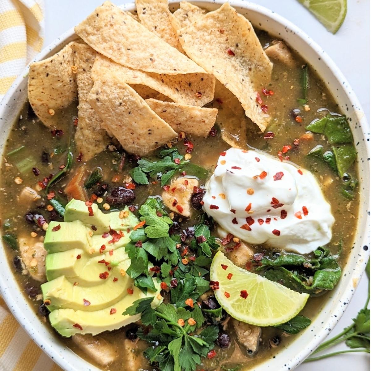 A bowl of delicious chicken tortilla soup garnished with avocado, cilantro, tortilla chips and a lime wedge