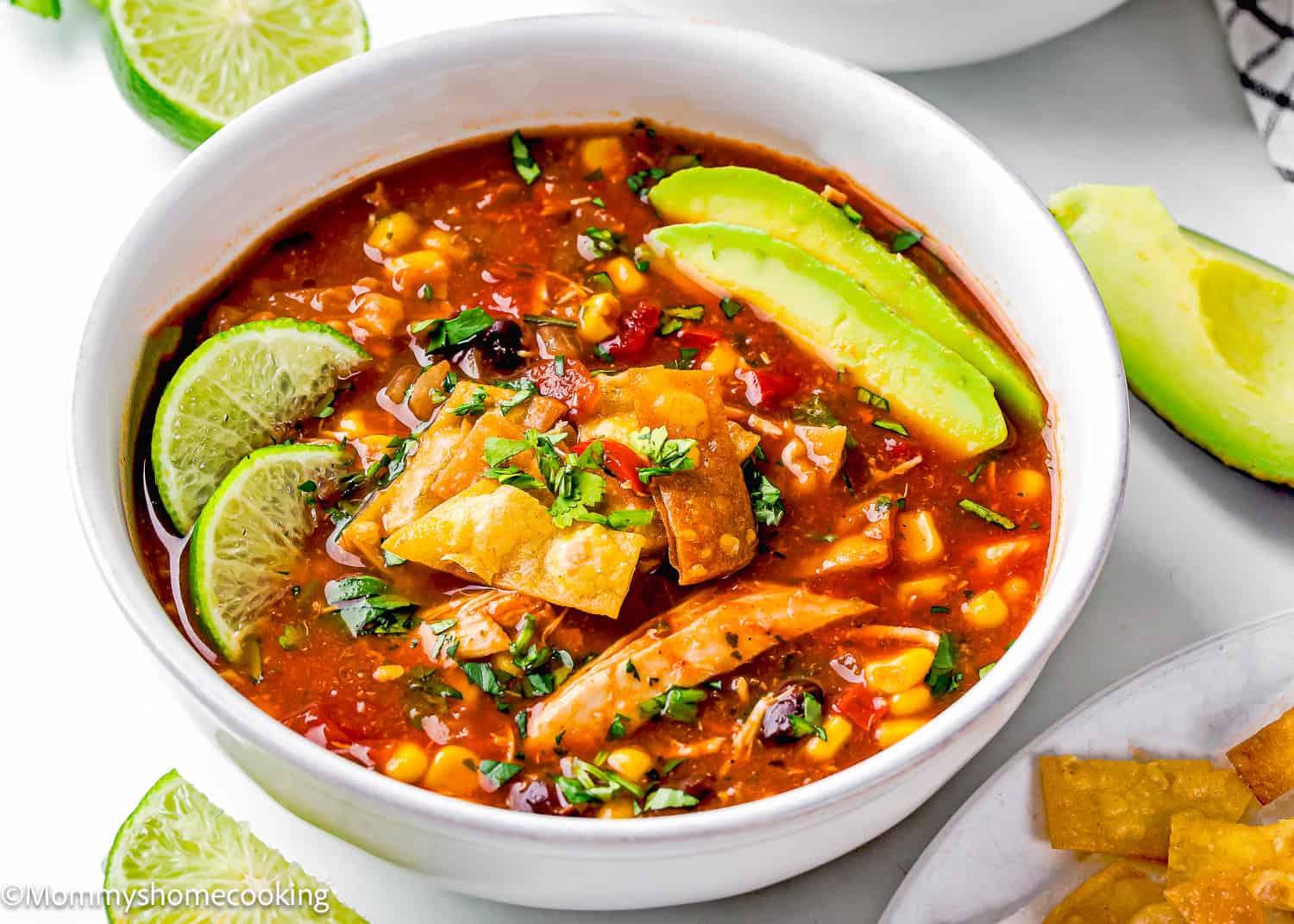A hearty bowl of zesty chicken tortilla soup garnished with avocado, cilantro, and tortilla strips
