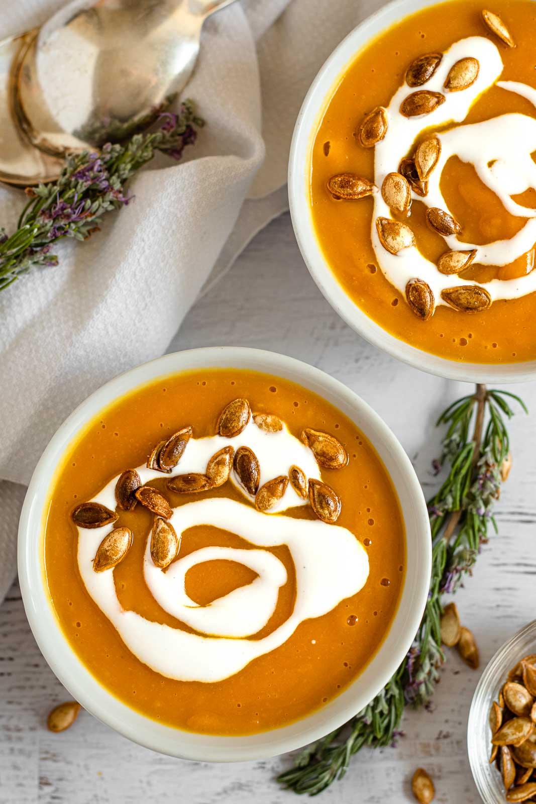 bowl of roasted garlic pumpkin soup garnished with rosemary and thyme