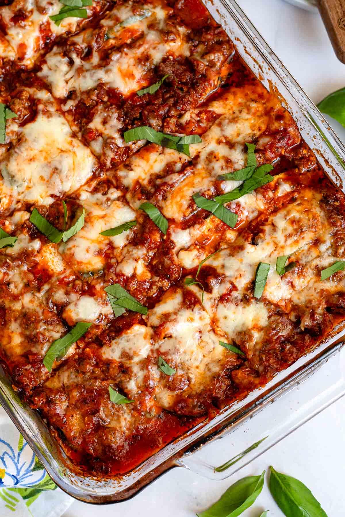 Assembling the zucchini lasagna: layering zucchini, meat sauce, ricotta, and mozzarella in a baking dish