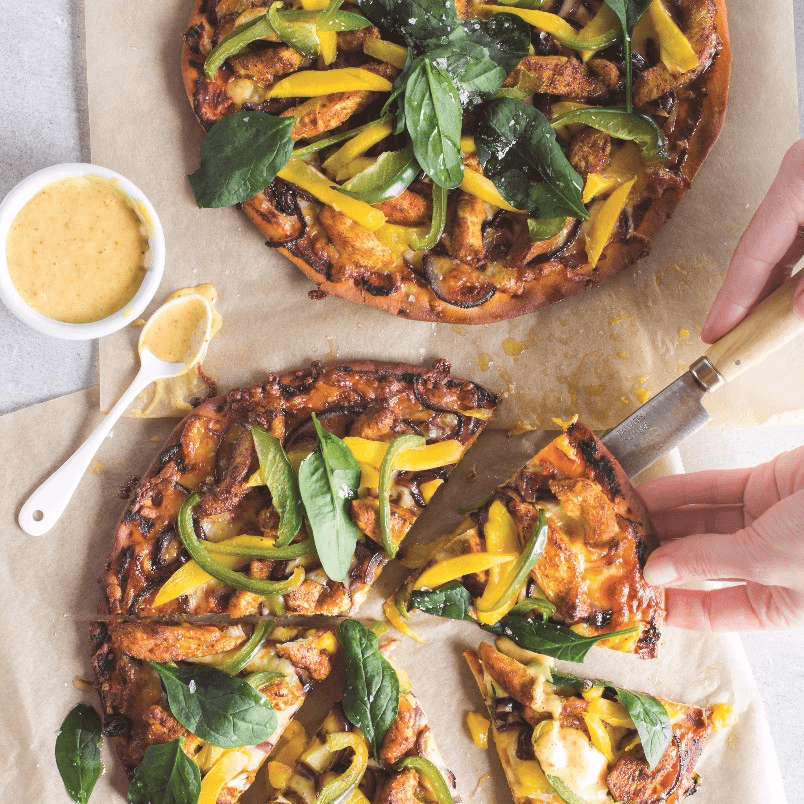 overhead shot of a mango chicken curry pizza with fresh cilantro garnish