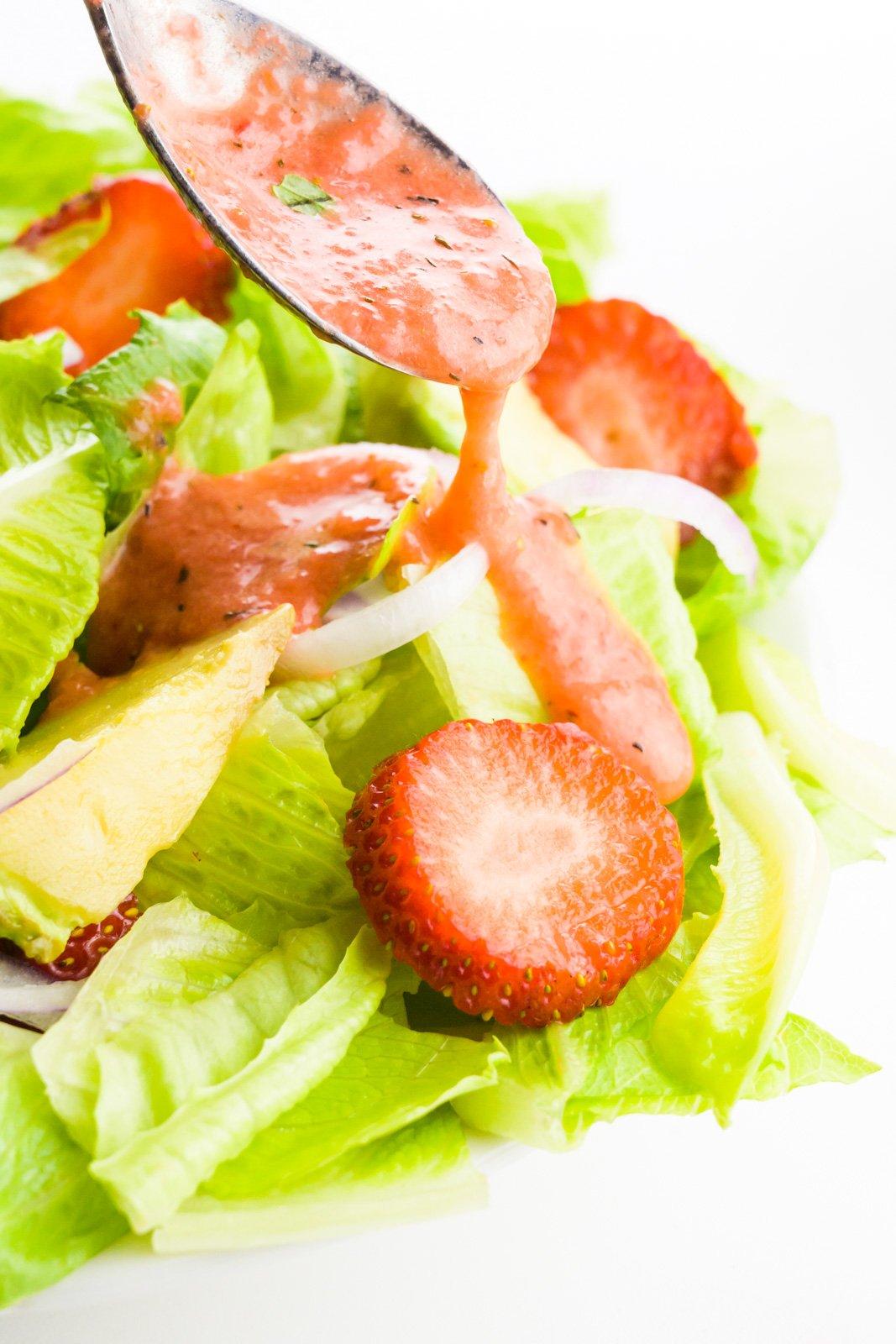 Close-up of strawberry vinaigrette being drizzled over a salad