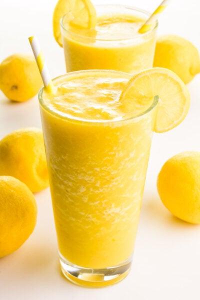 vibrant lemon almond smoothie in a glass with lemon slices and almonds