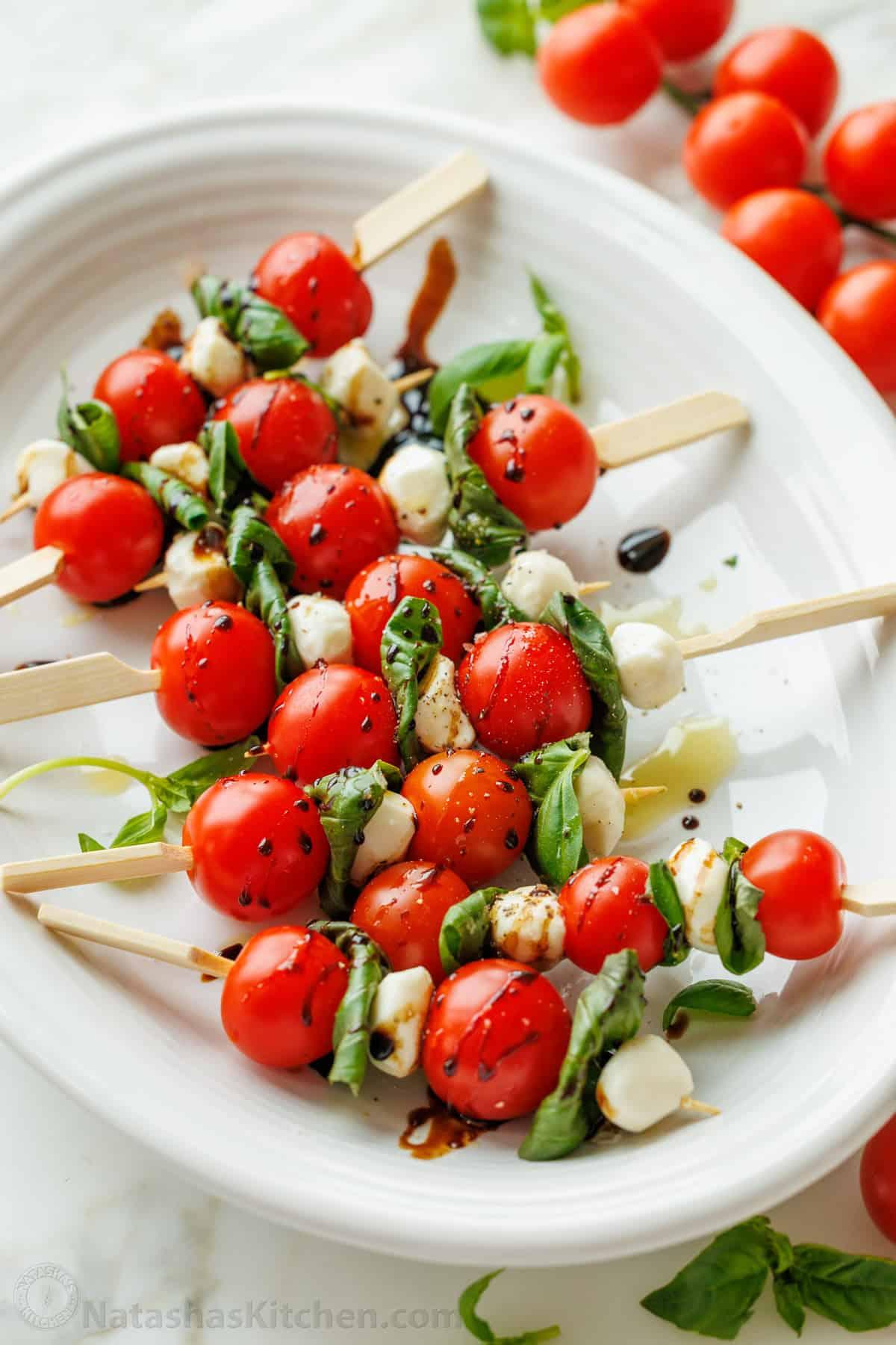 person quickly assembling caprese skewers in a bright kitchen with a playful expression