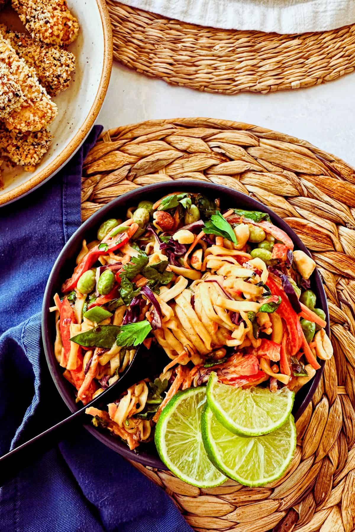overhead shot of a vibrant Thai peanut noodle salad in a picnic basket