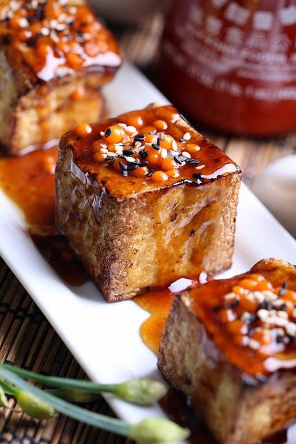 close-up of a single sriracha glazed tofu slider showing the texture of the tofu and glaze