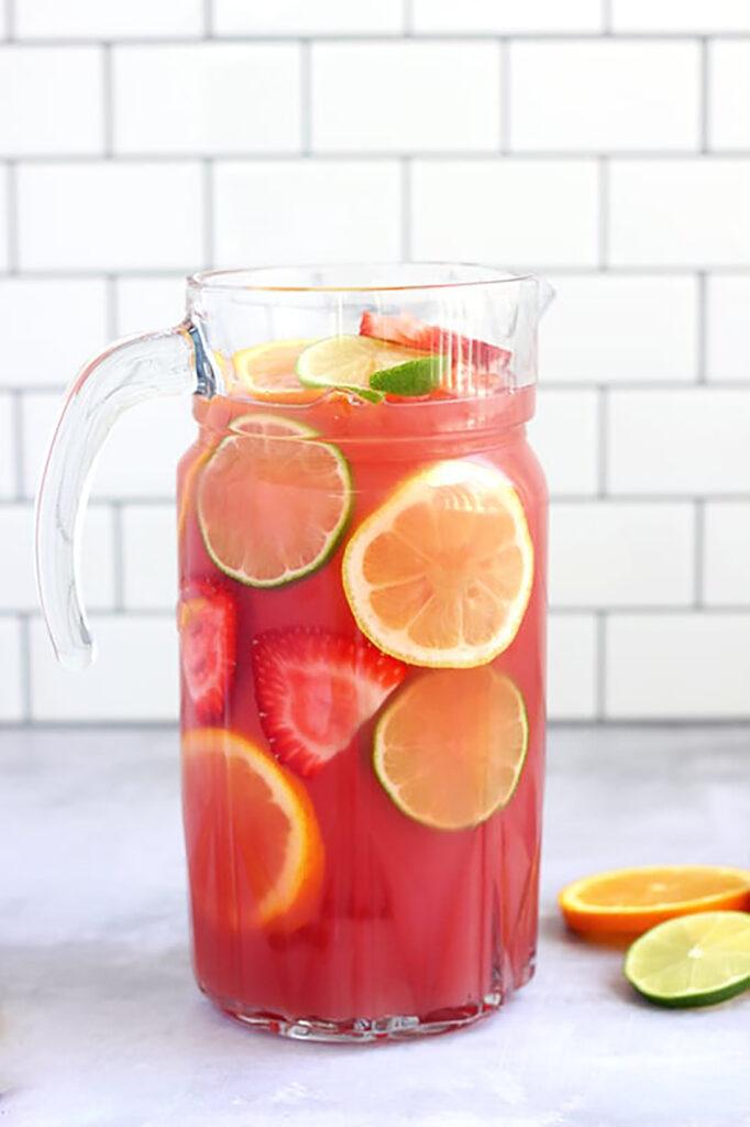 Refreshing fruit punch in a large glass pitcher with ice and fruit slices