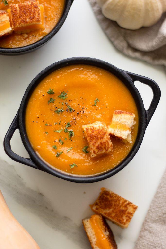 hearty Thanksgiving harvest vegetable soup with croutons and herbs, cozy autumn setting, warm lighting