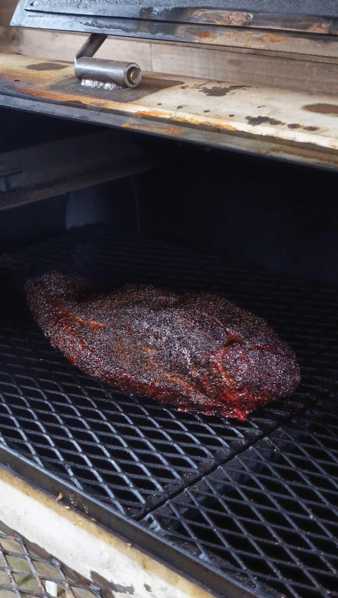brisket being smoked in a smoker, with visible smoke