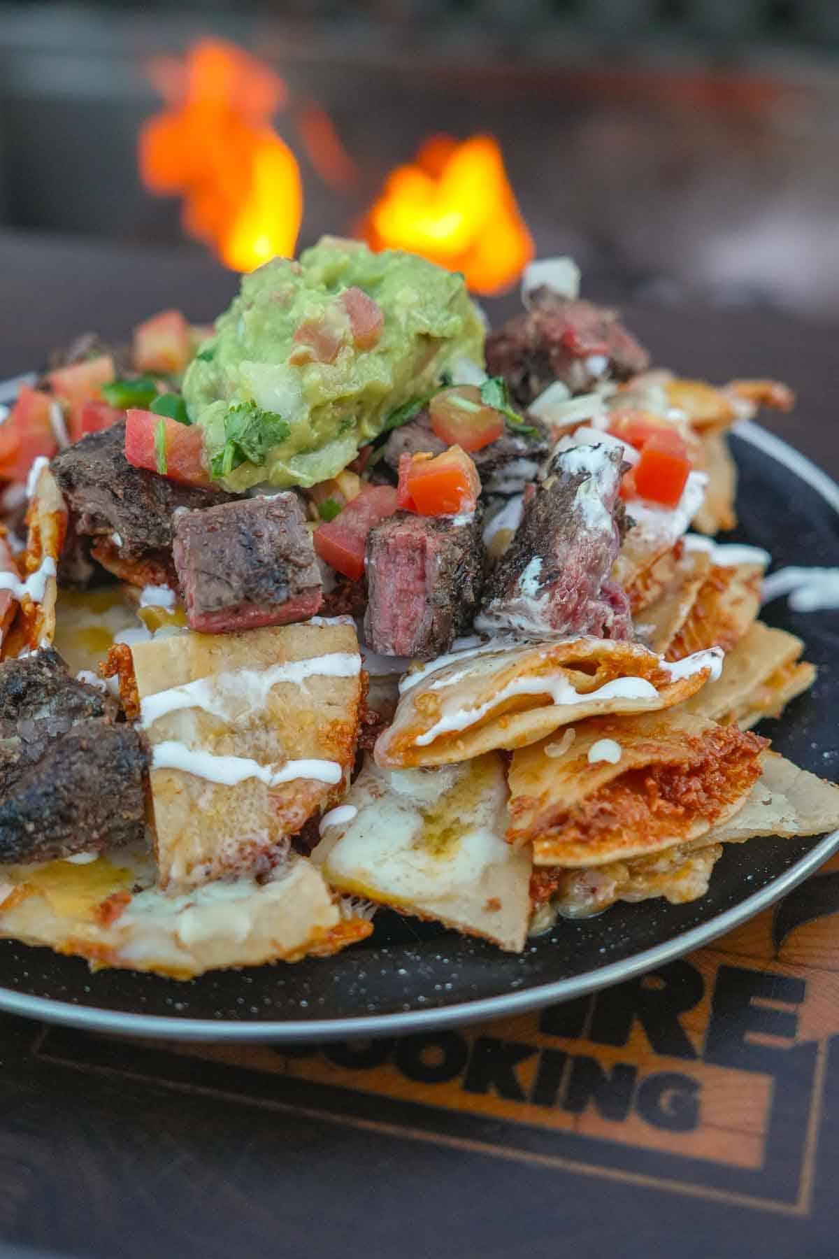 close-up of feijoada nachos with melted cheese and fresh toppings