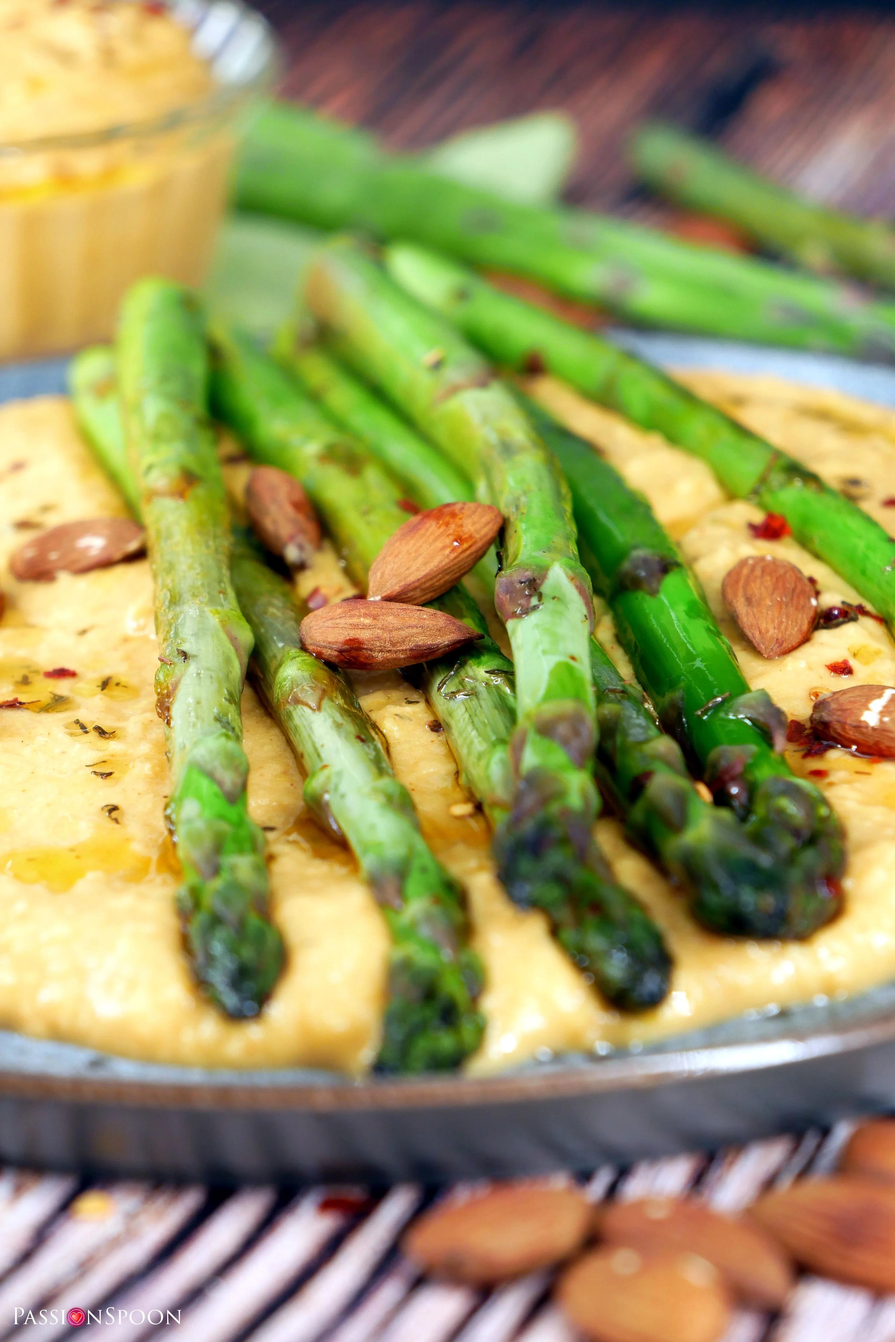 close up shot of creamy homemade hummus with asparagus spears