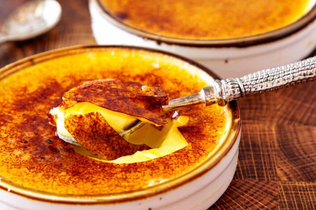 brown butter sage crème brûlée with a spoon cracking through the caramelized sugar crust