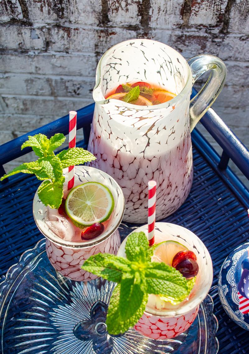 overhead shot of a picnic table with a pitcher of cherry almond lemonade and glasses