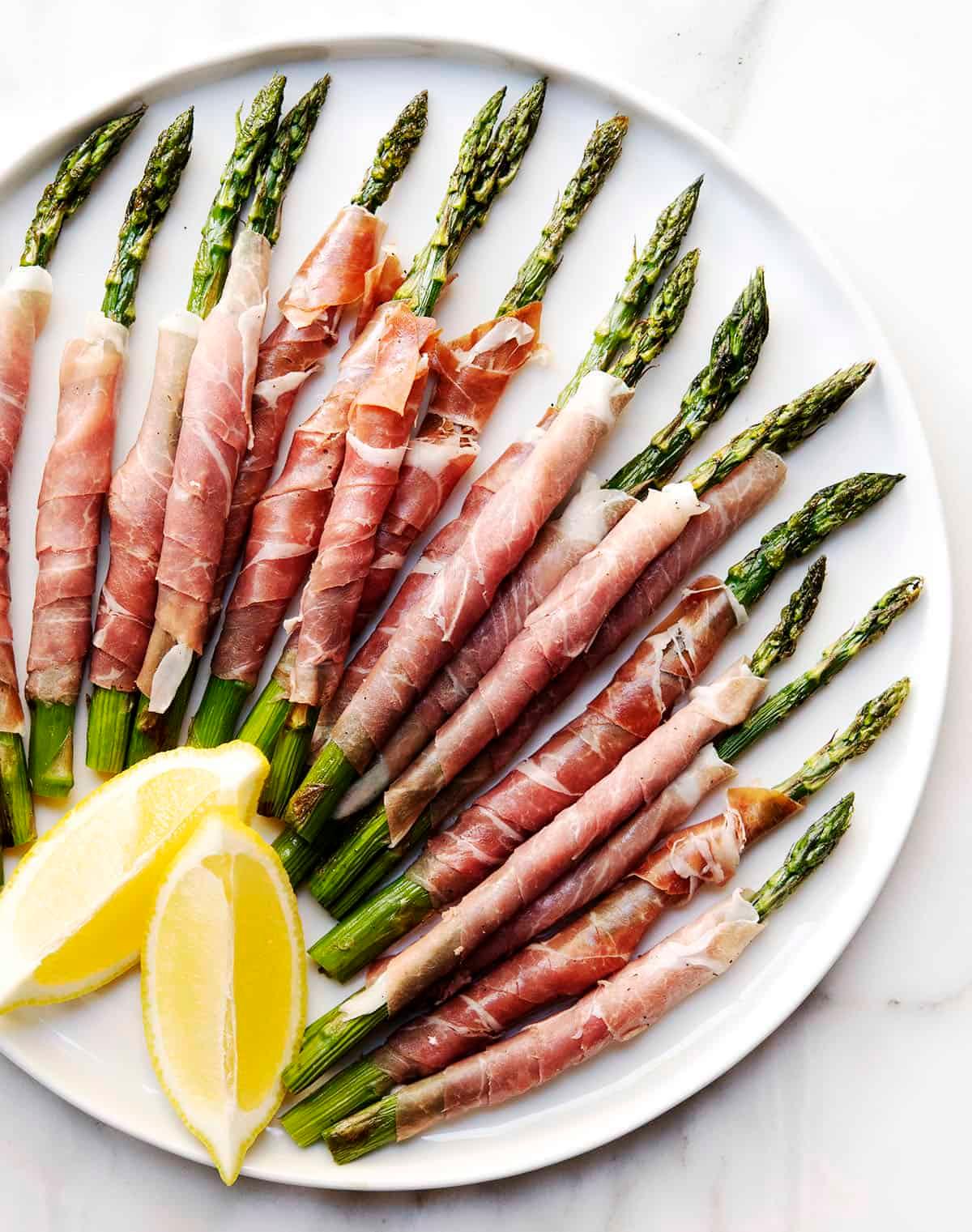Chef arranging prosciutto wrapped asparagus on a platter