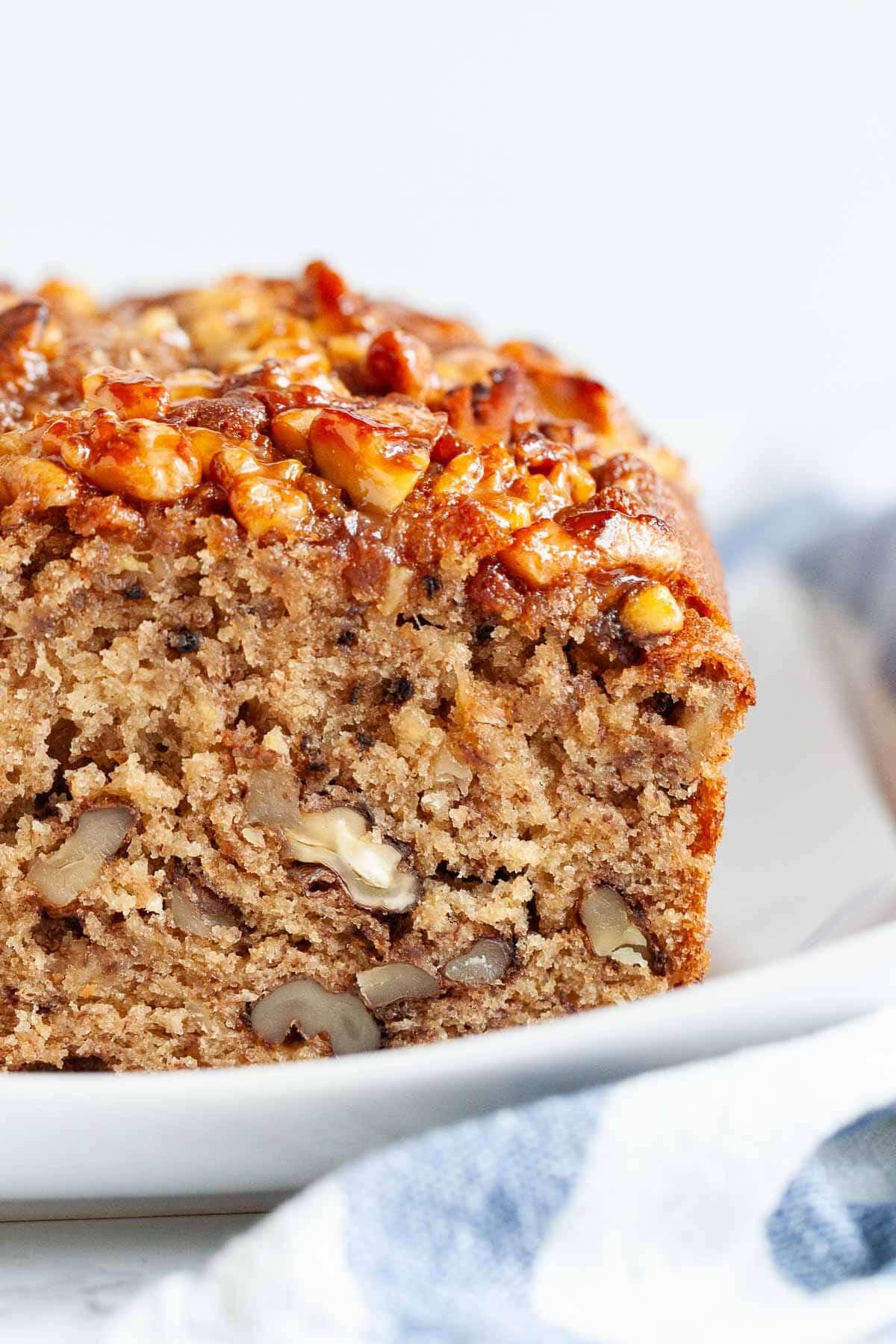 Slice of moist banana bread with walnuts on a plate, close up