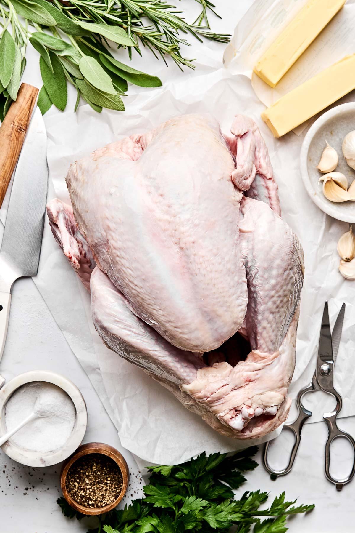chef's hands preparing a raw turkey with fresh rosemary and lemon, close up
