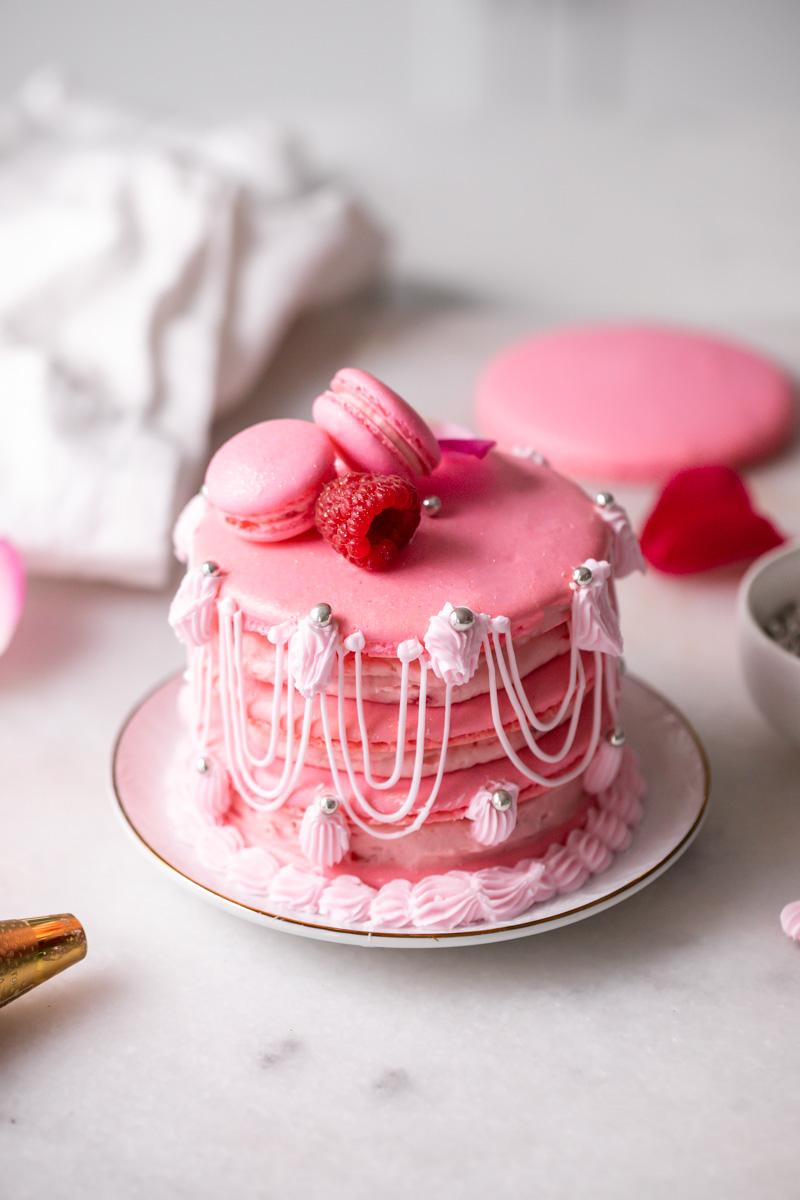 close up of a raspberry rose macaroon cake being assembled, showing the layers