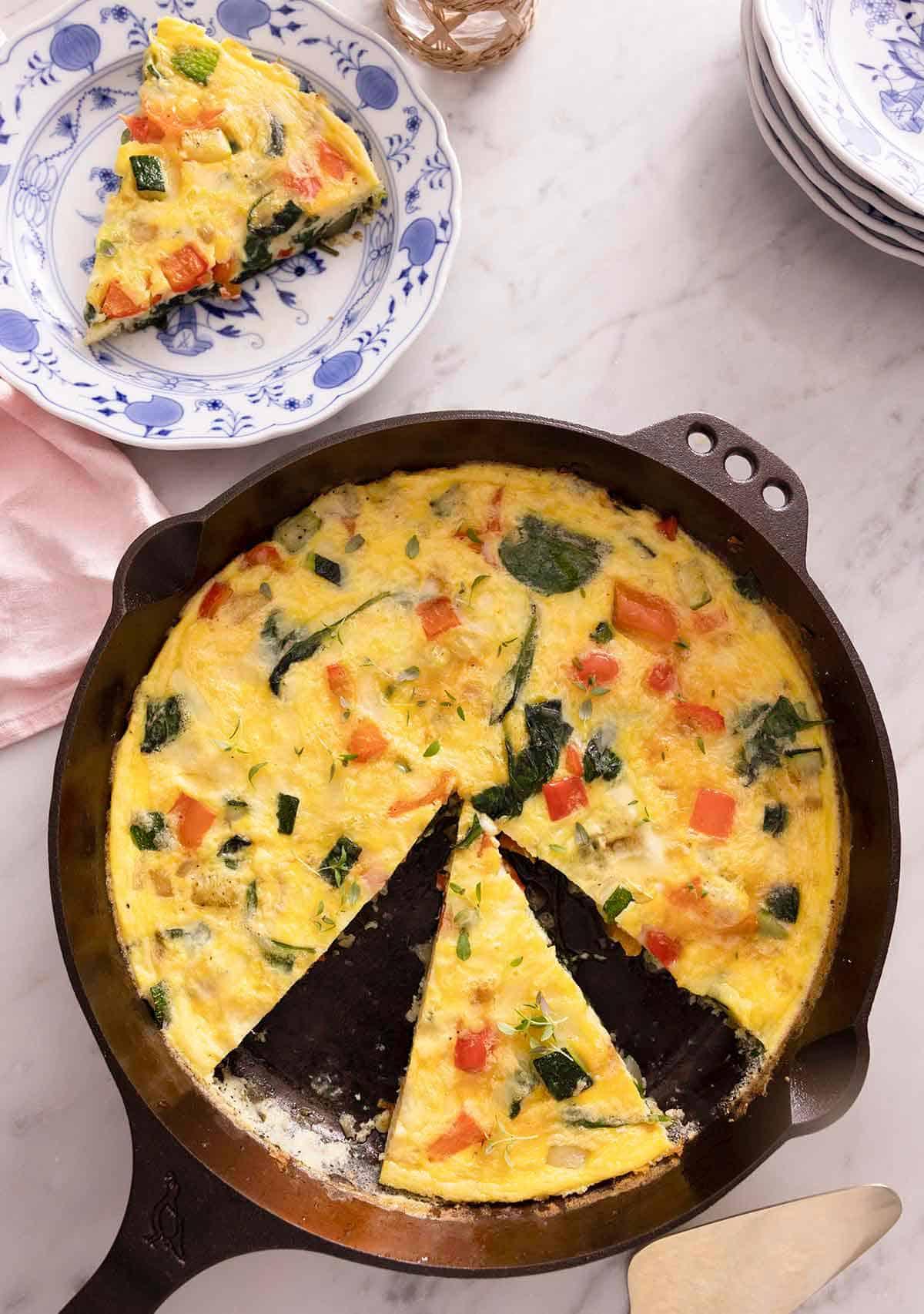 an overhead shot of a person slicing a frittata in a skillet