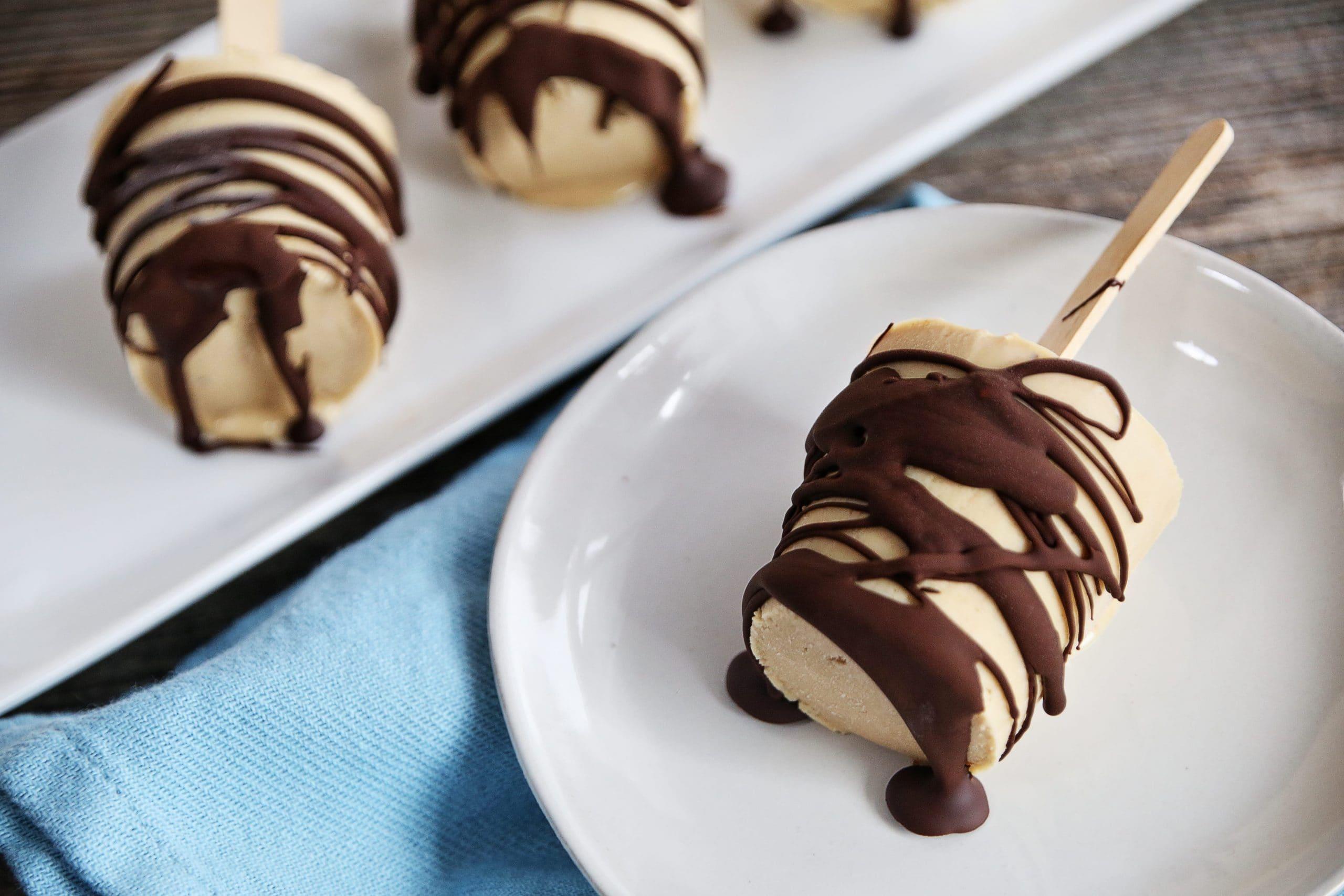 person drizzling melted chocolate over pear popsicles