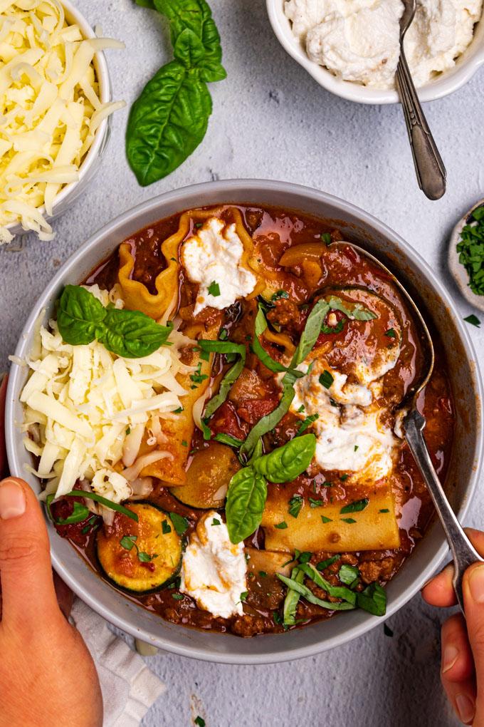 overhead shot of several bowls of lasagna soup garnished with ricotta and basil