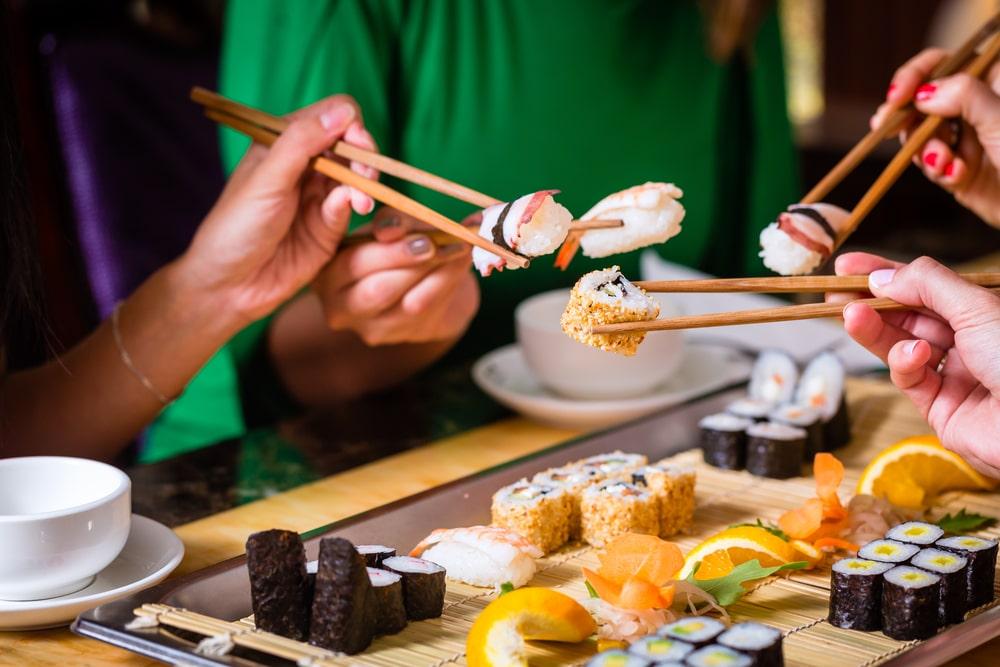 people eating sushi at a sushi bar