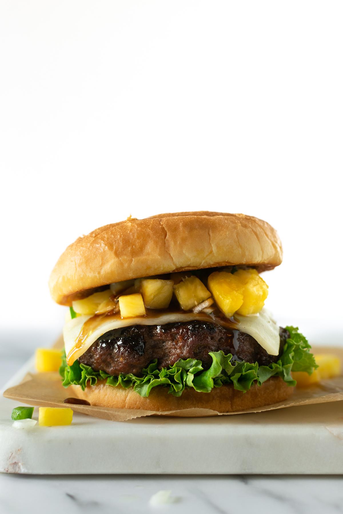 A hand adding Pineapple Salsa to a burger patty