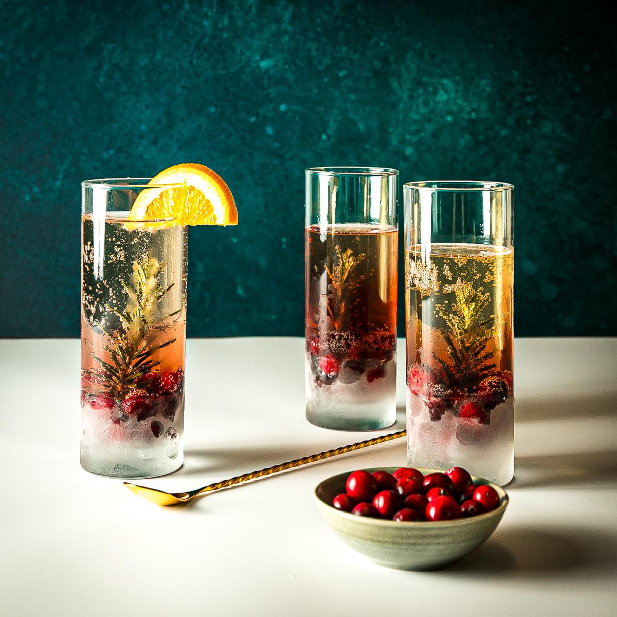 elegant non-alcoholic sparkling holiday drink in a flute glass with cranberries and a rosemary sprig